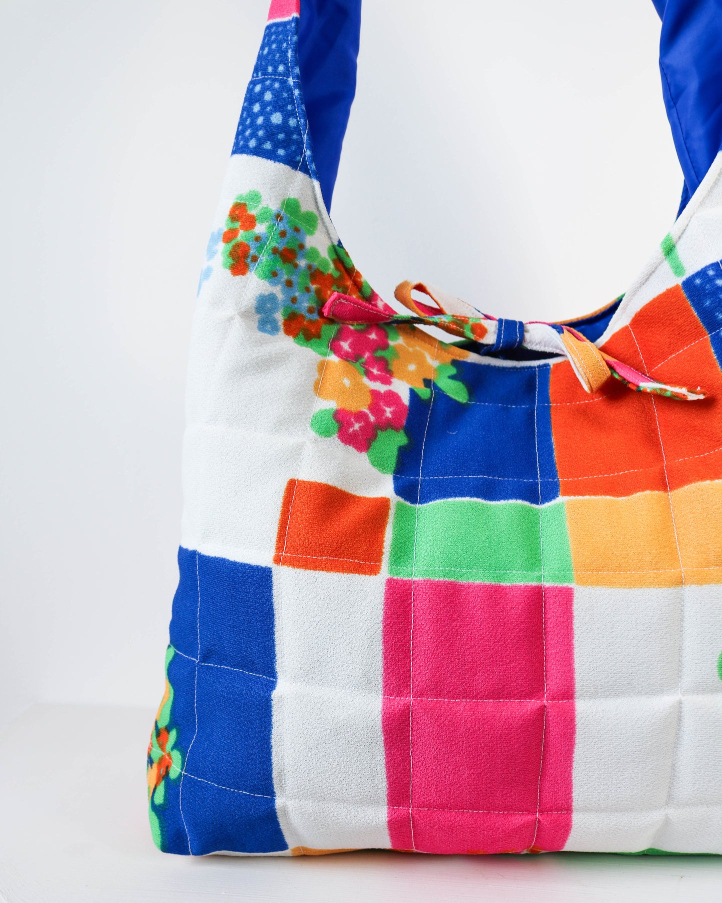 Colorful patchwork bag with floral accents on a white background