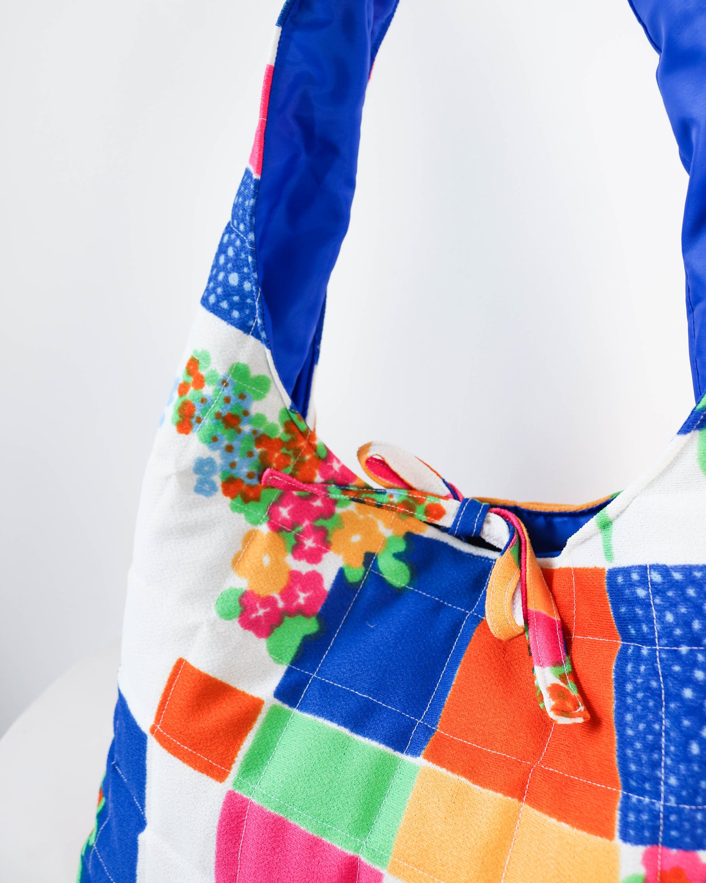 Colorful patchwork bag with floral design on a white background