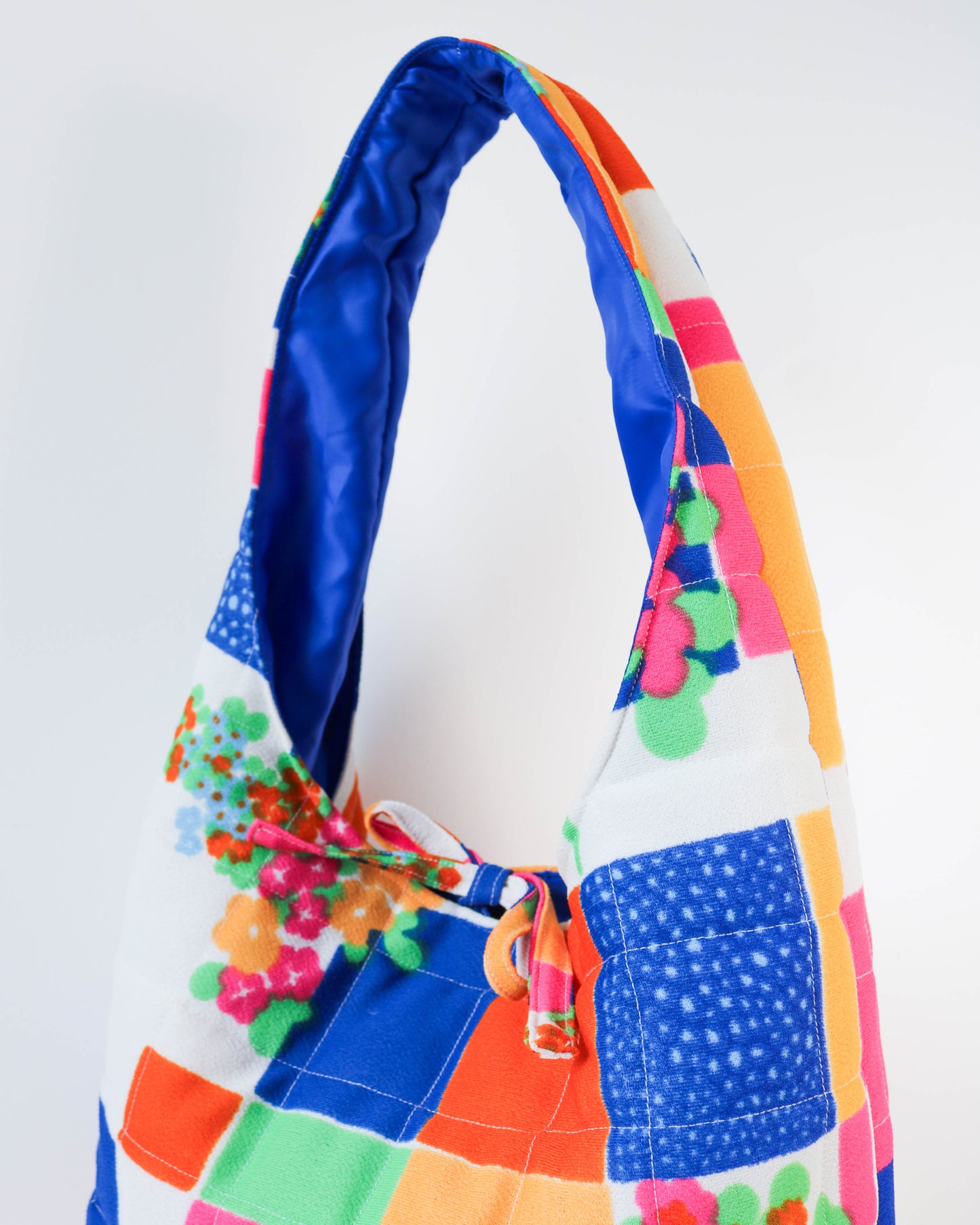 Colorful patchwork bag with floral accents on a white background