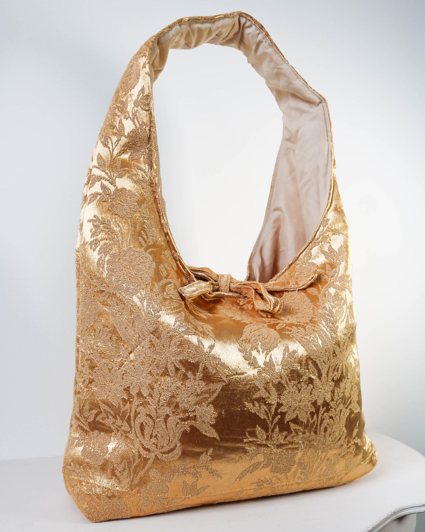 Gold floral patterned handbag on a white background