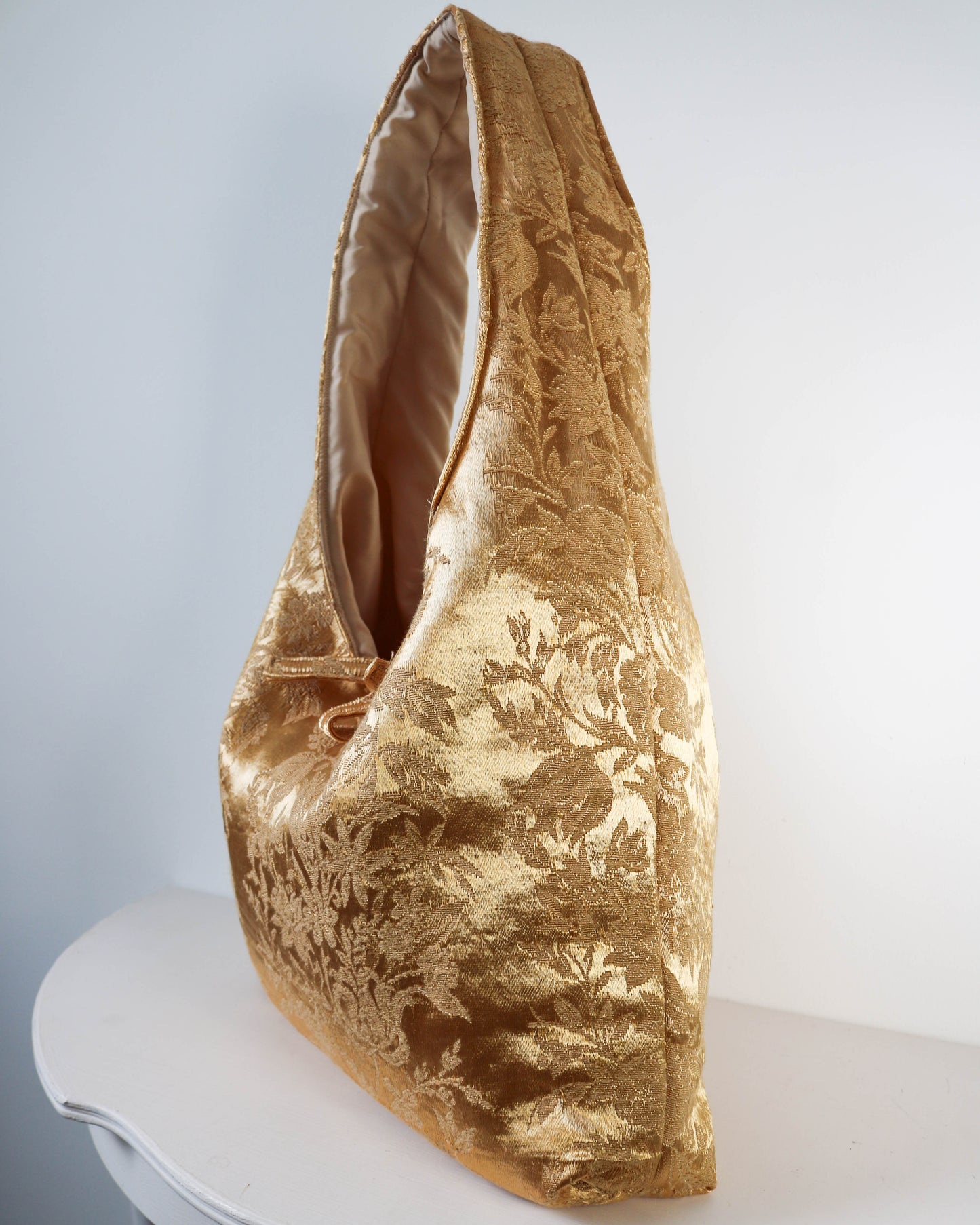 Gold textured handbag on a white surface with a light gray background