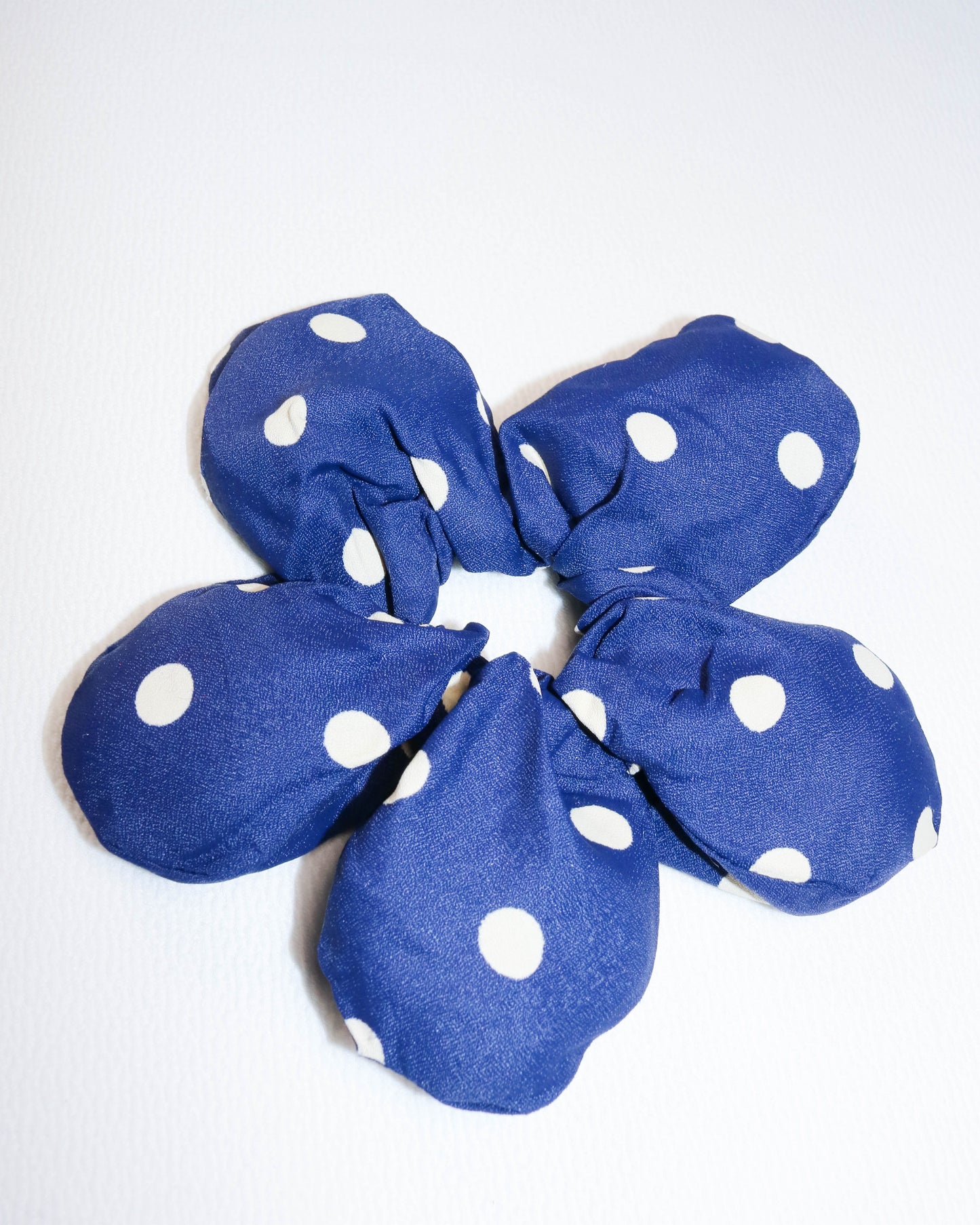 Blue scrunchie with white polka dots on a white background