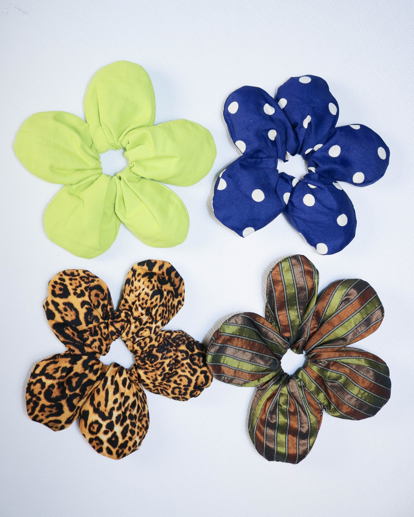 Four colorful scrunchies with different patterns on a white background