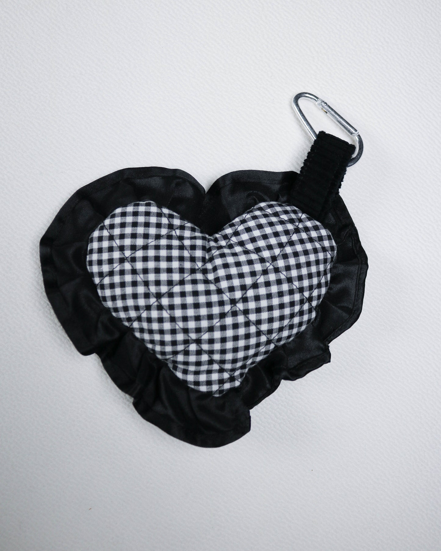 Black and white checkered bag charm with a carabiner on a light gray background