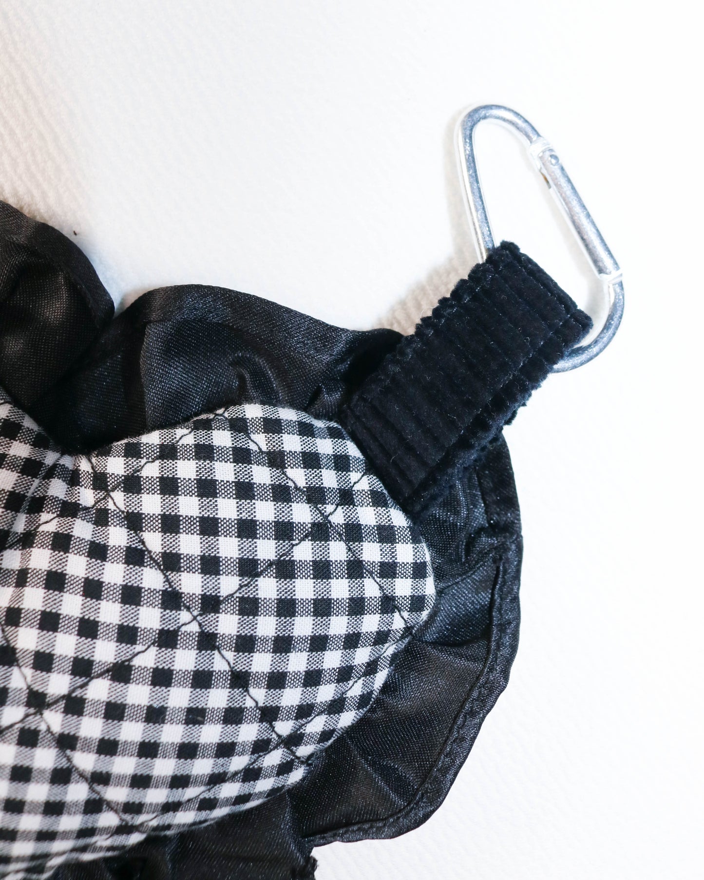 Black and white checkered fabric with a carabiner on a white background