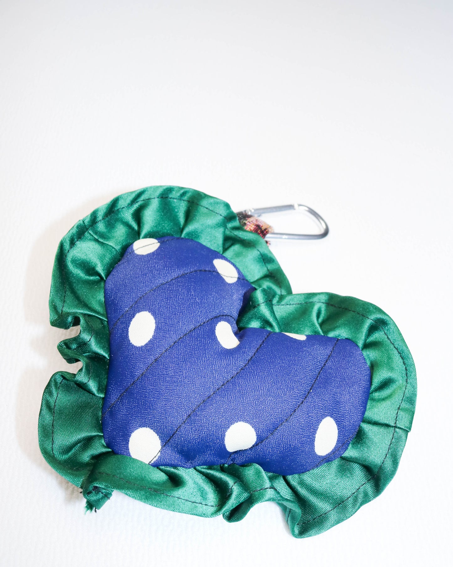 Blue polka dot bag charm with green cover on a white background