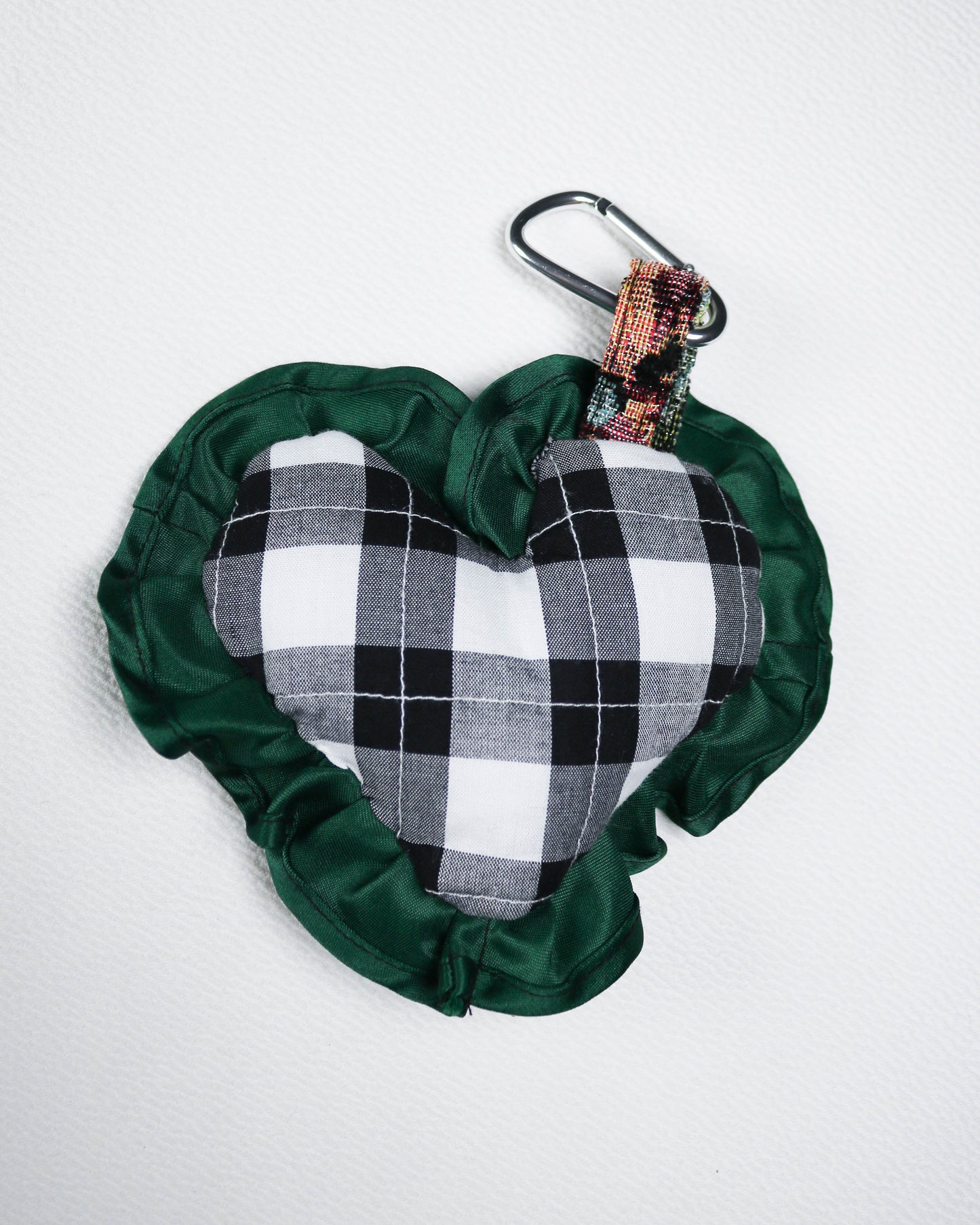 Heart-shaped bag charm with plaid interior and green exterior on a white background