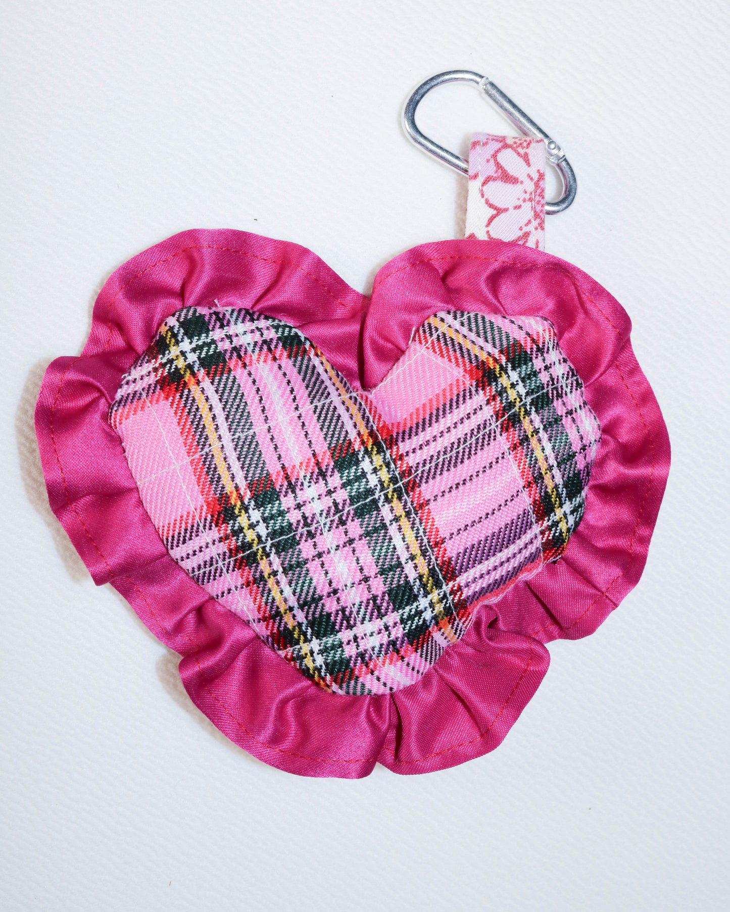 Pink fabric pouch with plaid pattern and carabiner on a white background