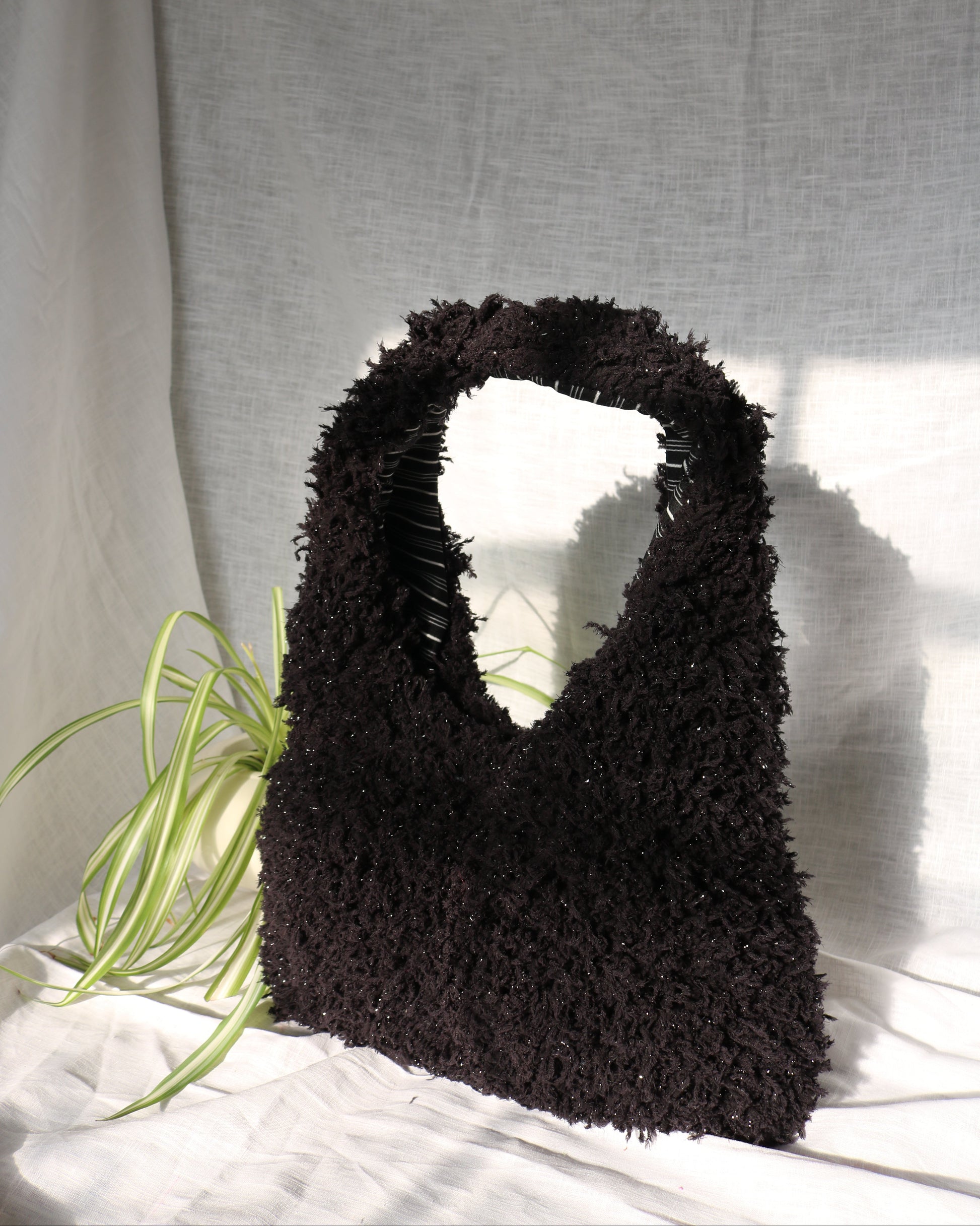 Black textured handbag on a light gray background