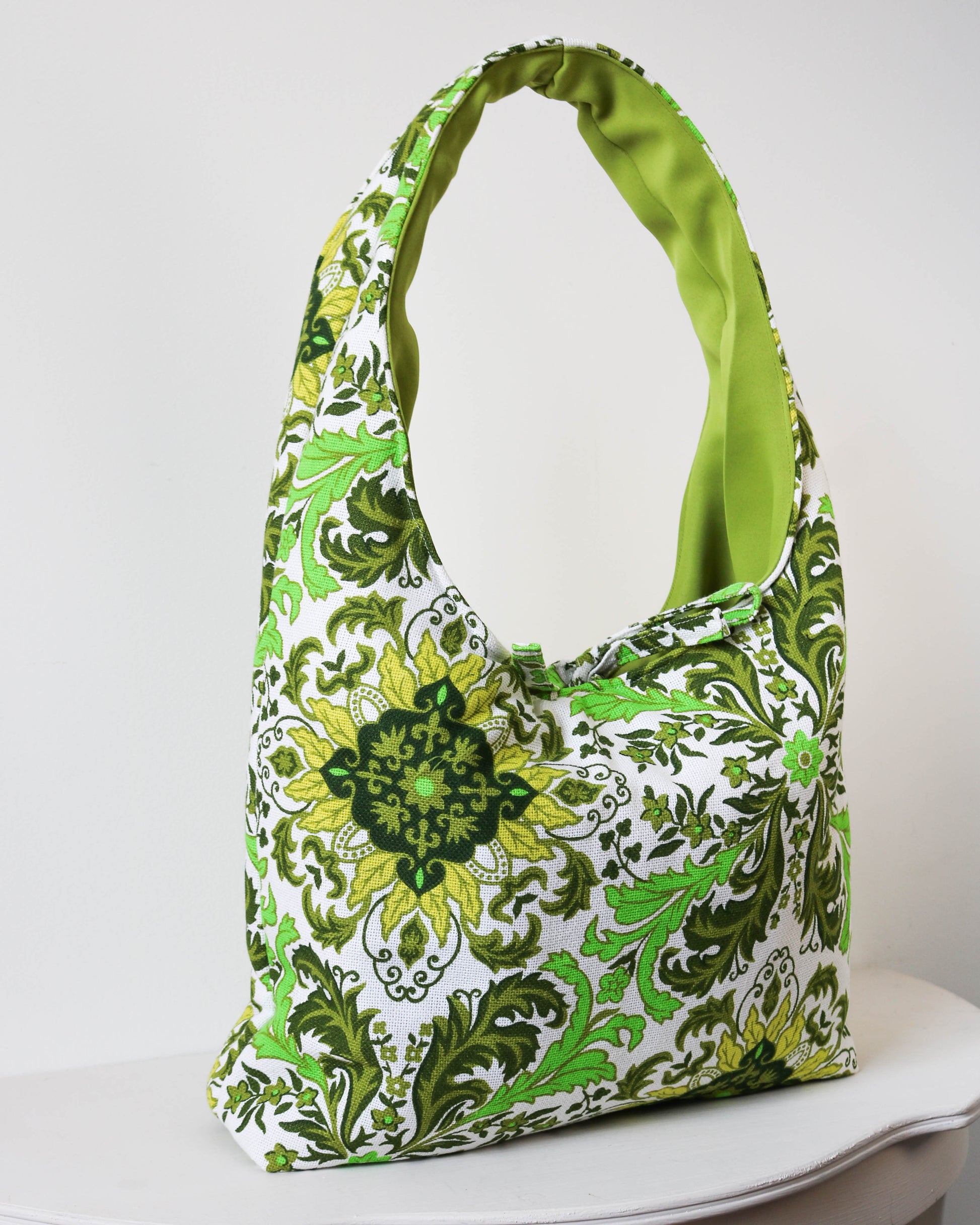 Green and white patterned handbag on a white surface with a white background