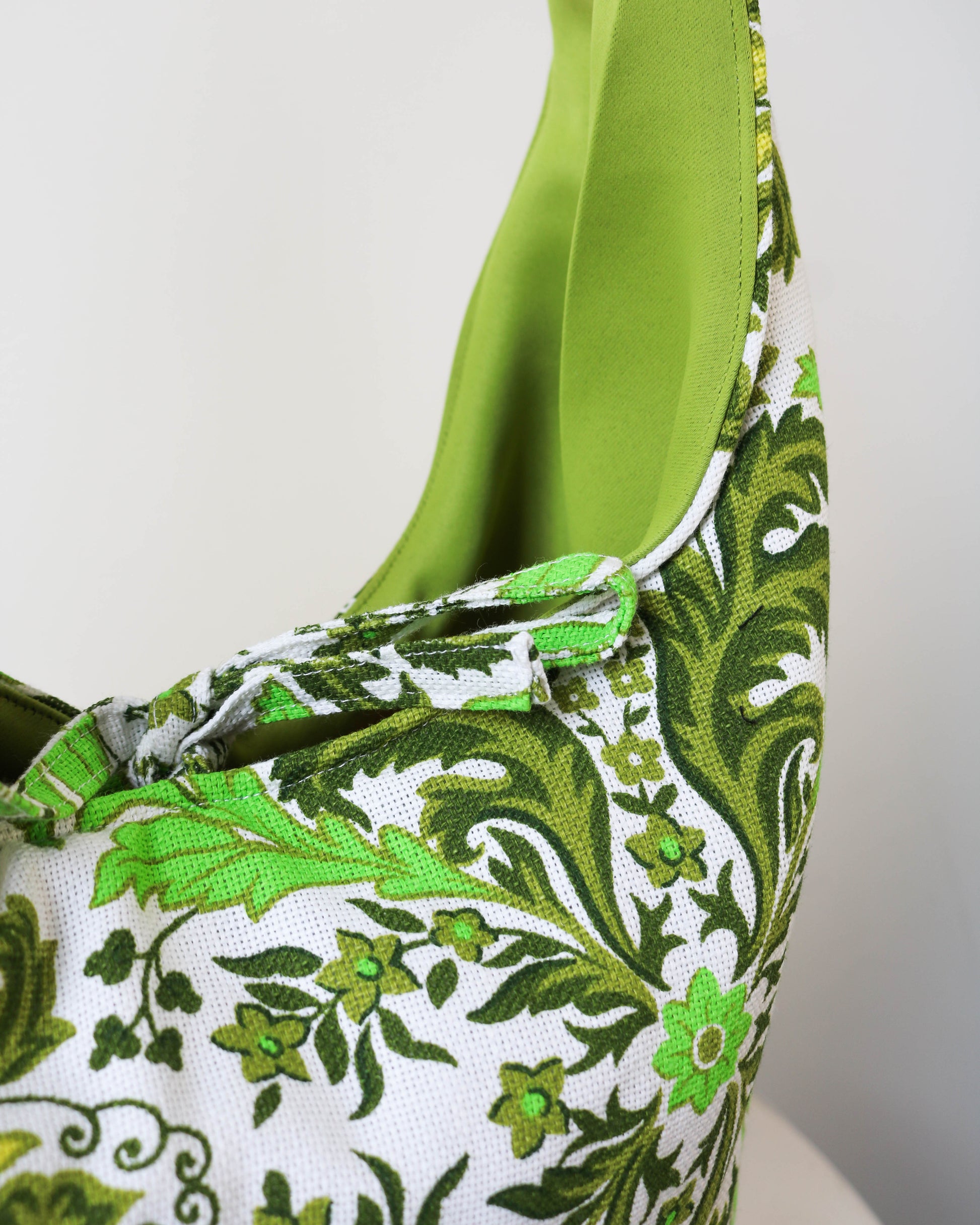 Green and white floral patterned bag with green handles on a white background