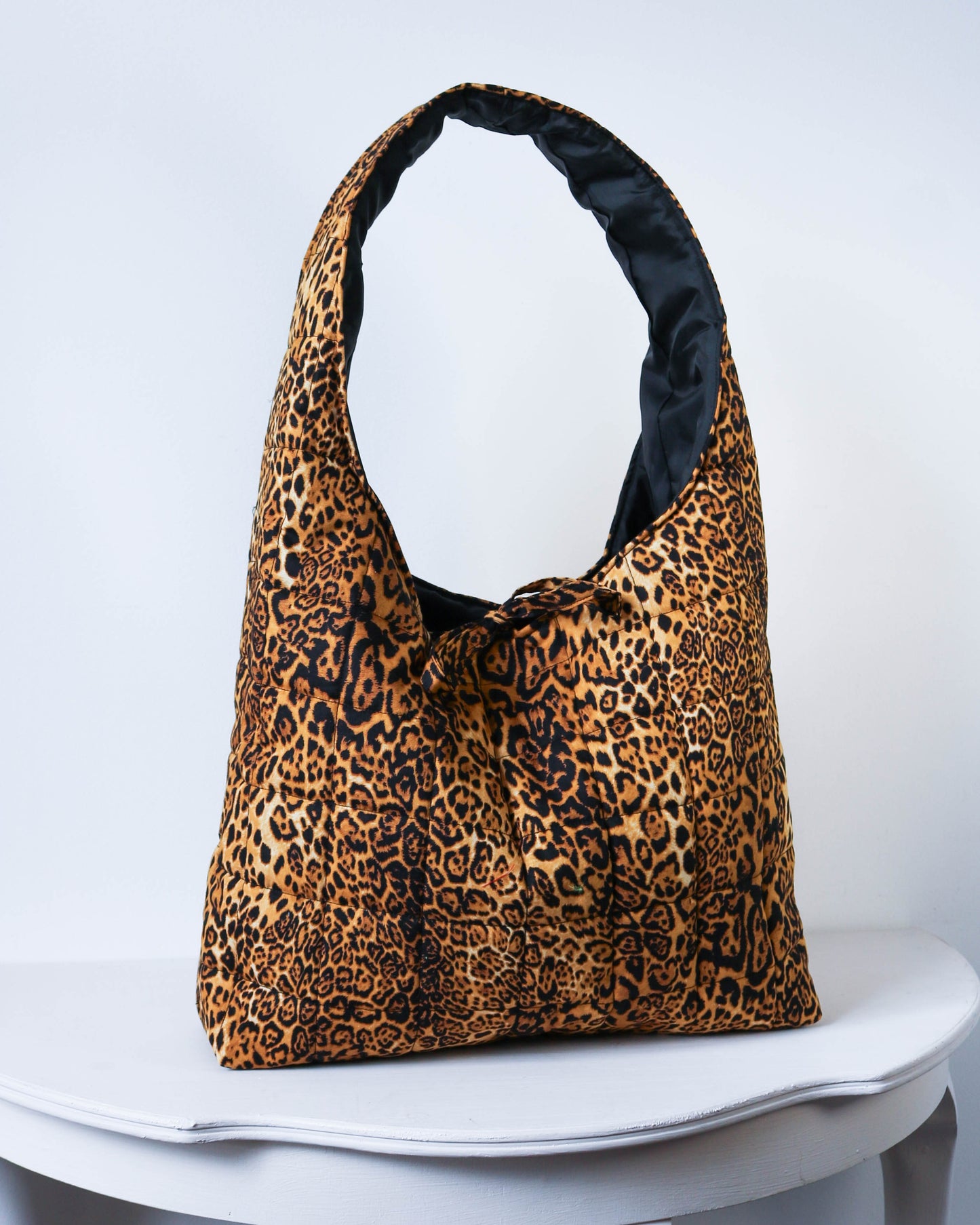 Leopard print bag with black interior on a white surface