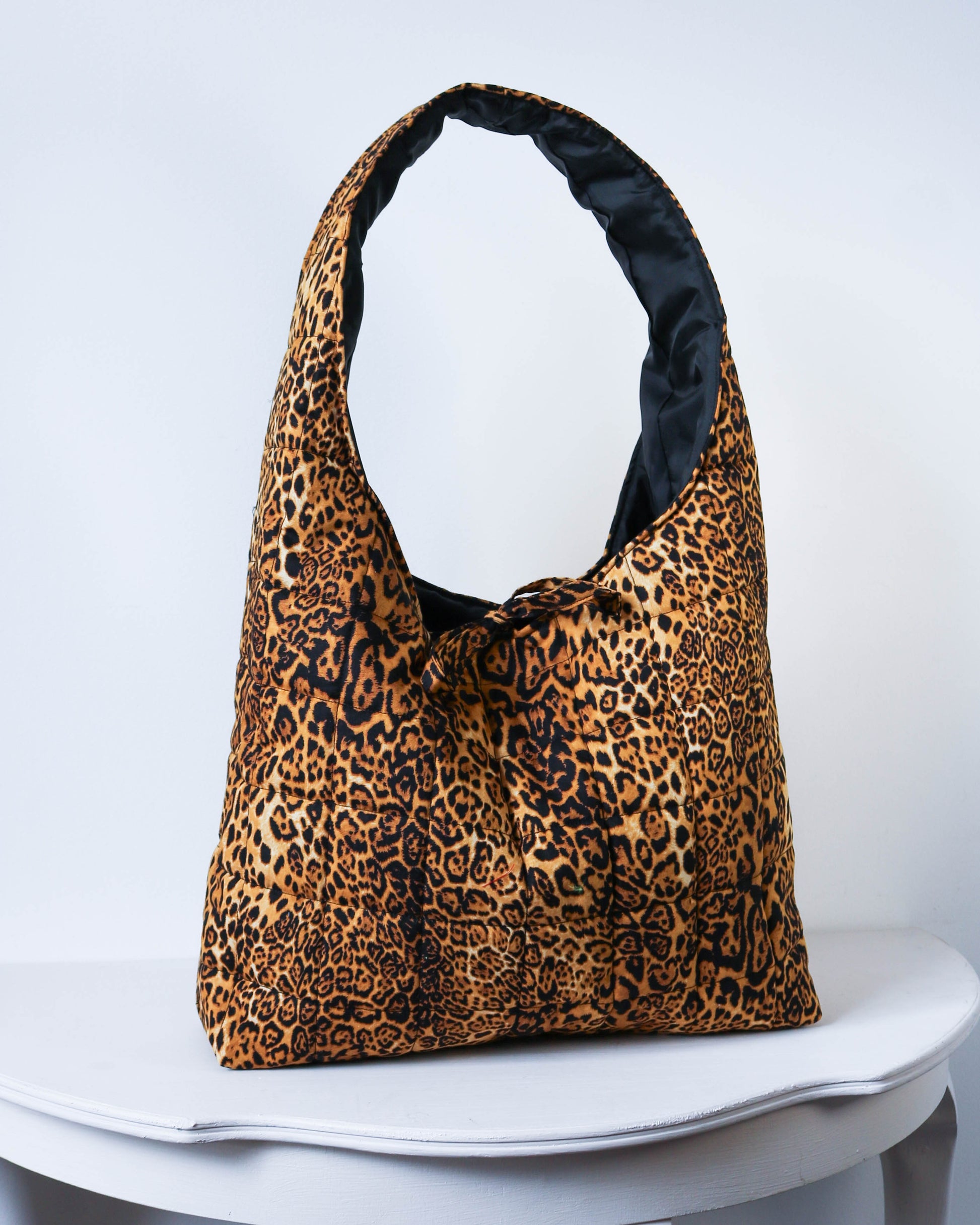 Leopard print bag with black interior on a white surface