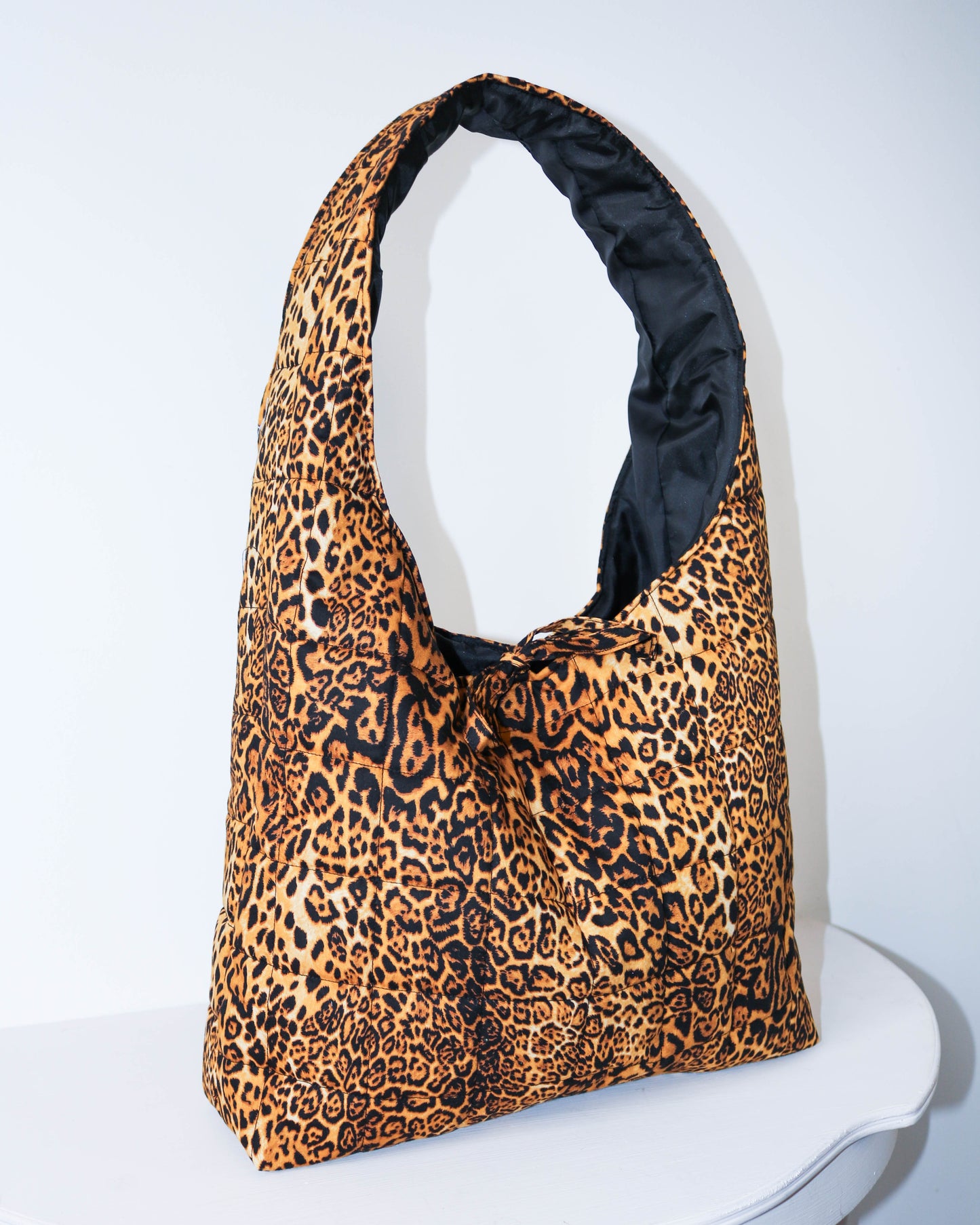 Leopard print bag with black interior on a white background