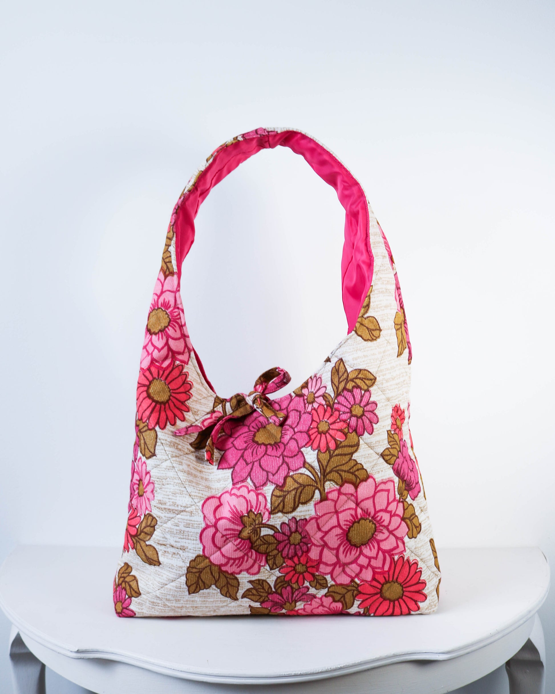 Floral handbag with pink handle on a white chair against a light gray background