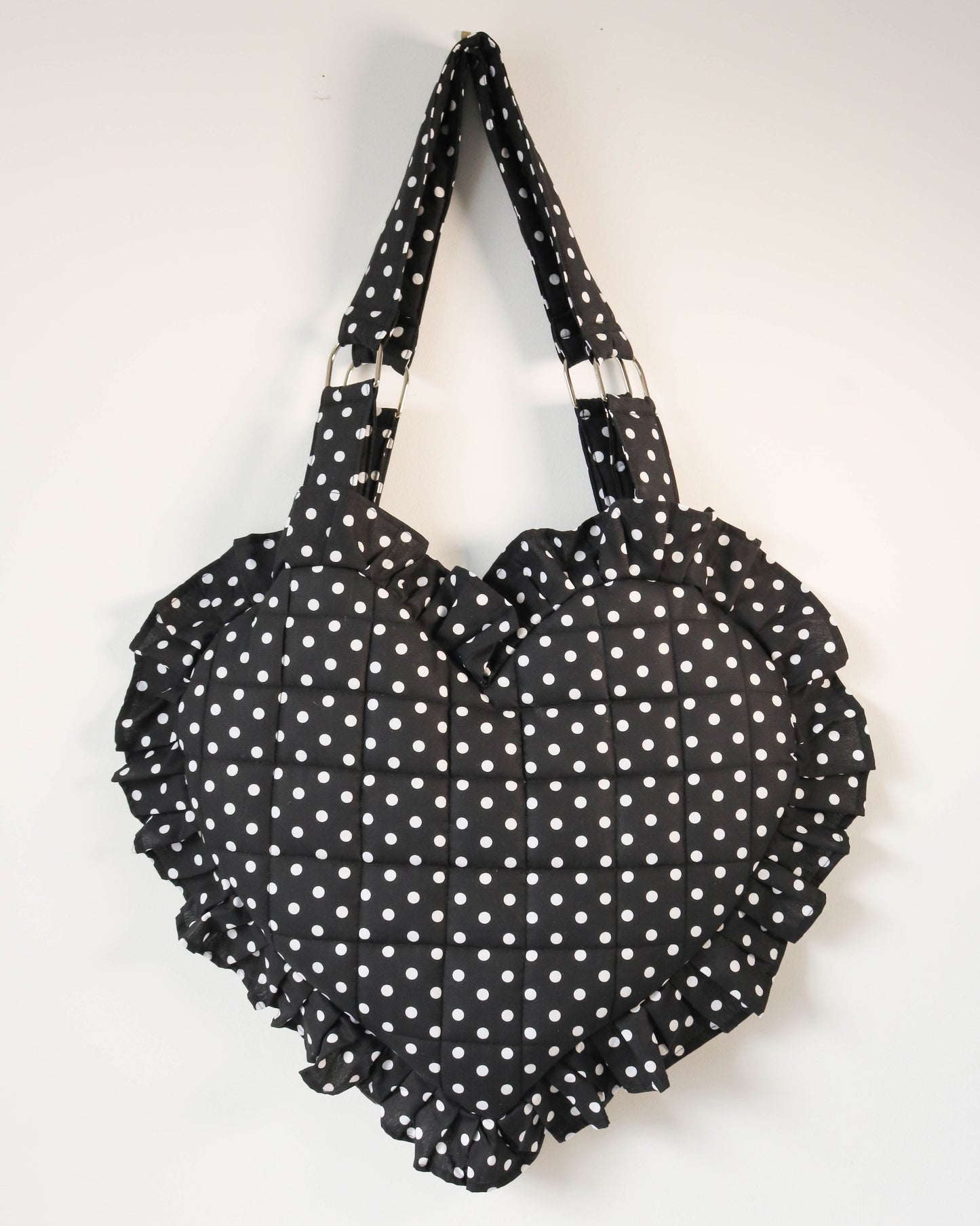 Black polka dot bag with ruffled edges on a white background