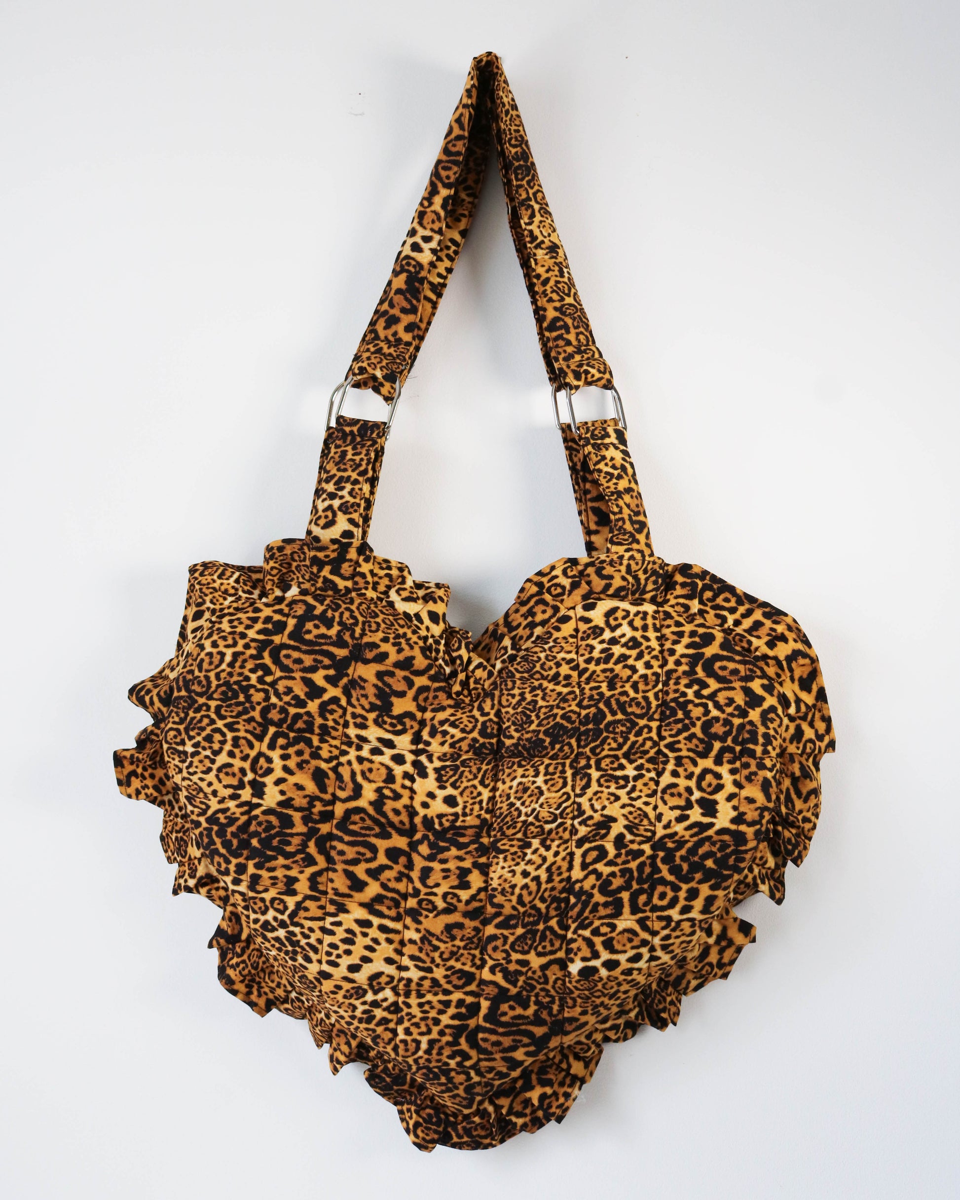 Leopard print handbag with ruffled details on a white background