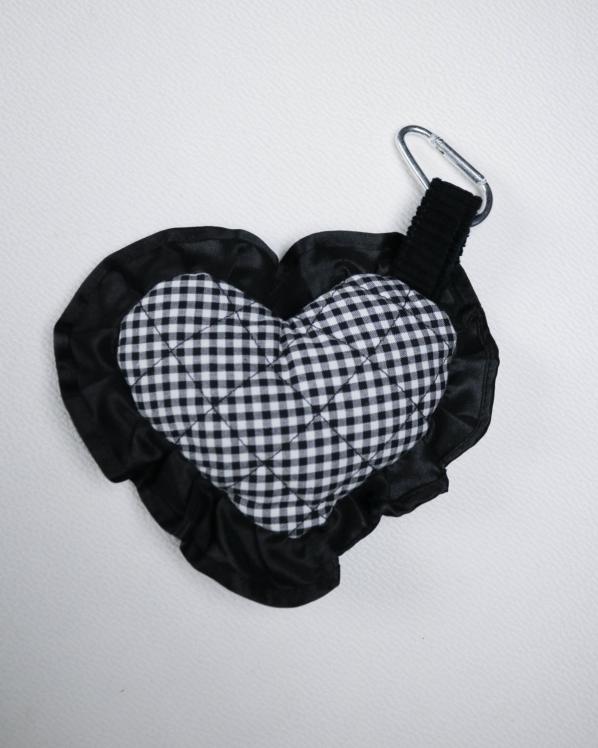 Black and white checkered bag charm with a carabiner on a light gray background