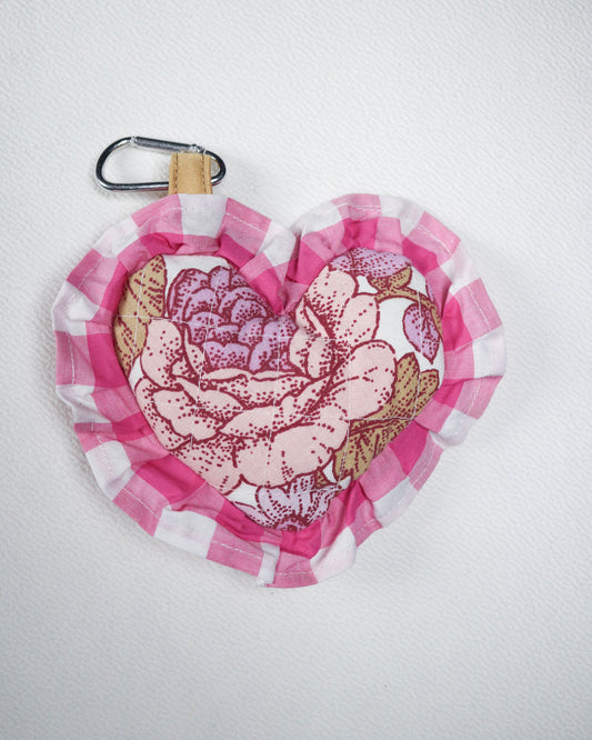 Pink floral patterned bag charm with a carabiner on a white background