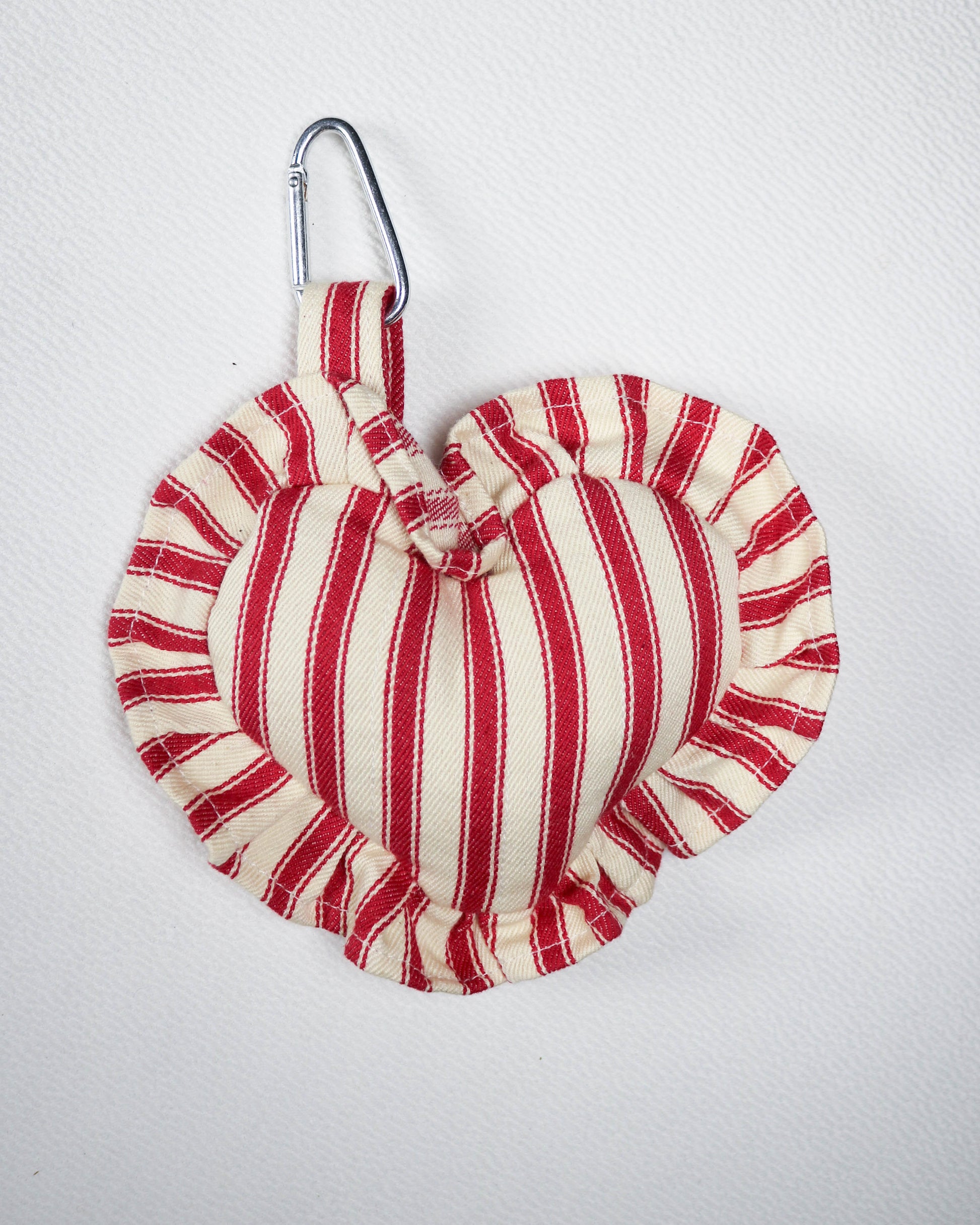 Red and white striped fabric bag charm with carabiner on a light gray background