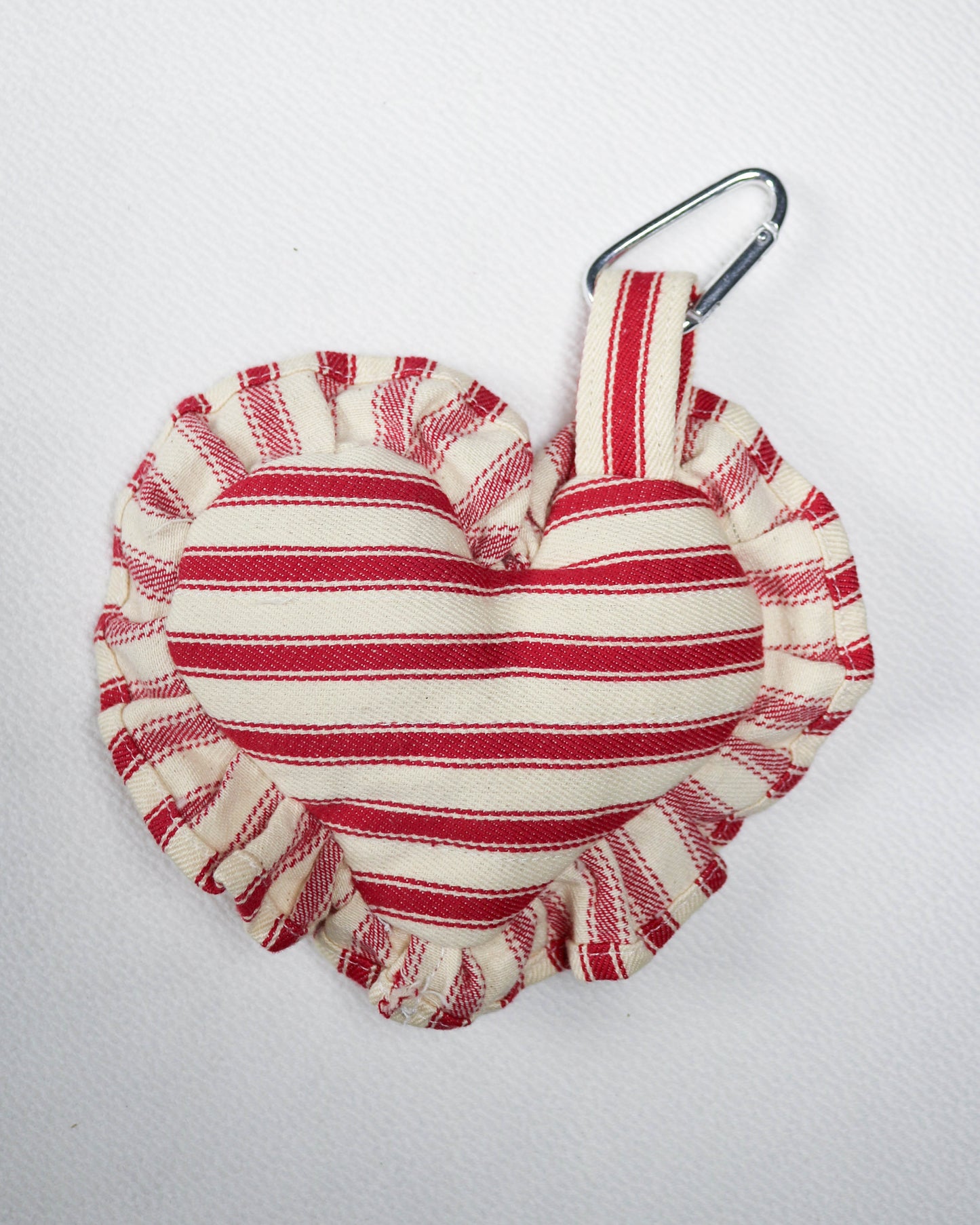 Red and white striped fabric key chain with a carabiner clip on a light gray background