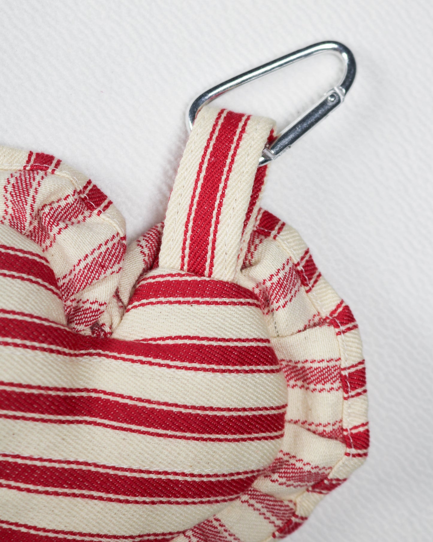 Red and white striped fabric with a metal carabiner on a light gray background