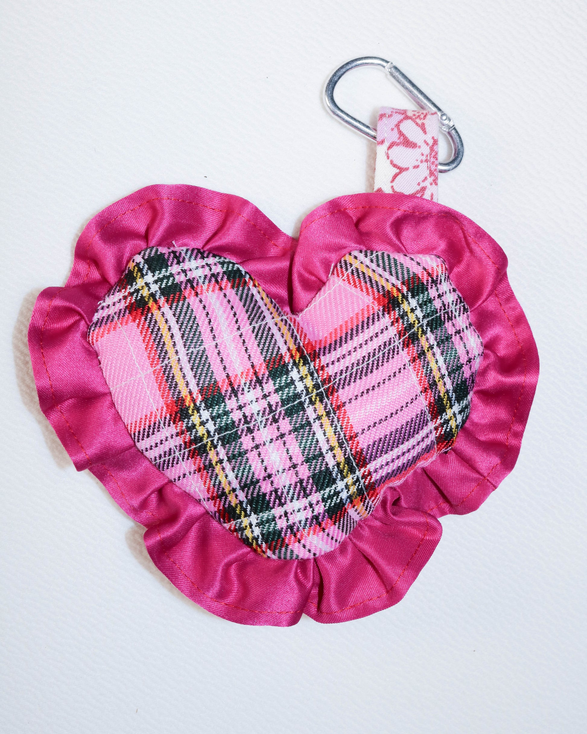 Pink fabric pouch with plaid pattern and carabiner on a white background